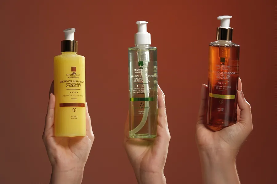 Tres manos sosteniendo los dermolimpiadores de vitamina E, aloe vera y regaliz