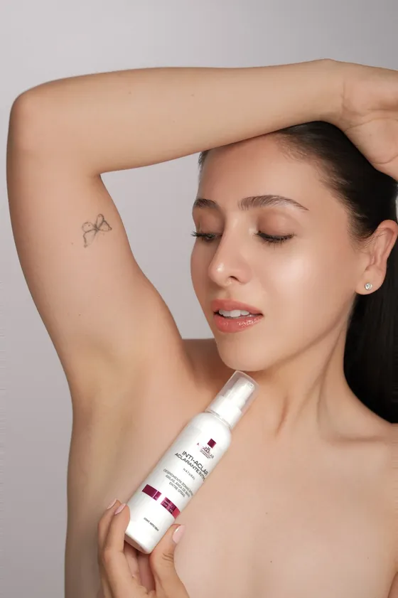 Mujer sosteniendo el Sérum Inti-Aclar junto a la axila